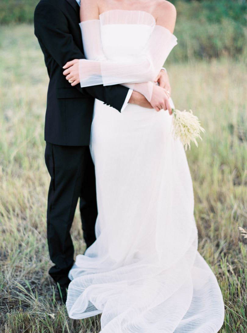 bride and groom embracing in grass field