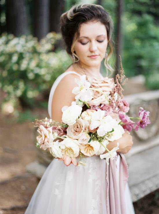 bride holding brirdal bouquet in the woods