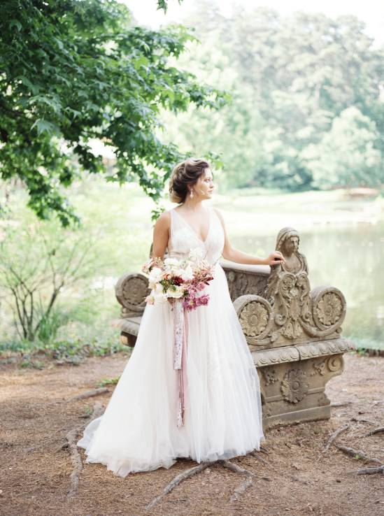 bride leaning on bench overlooking a lake