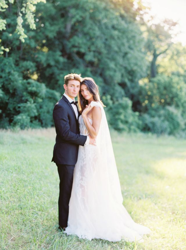 bride and groom posing in grassy field