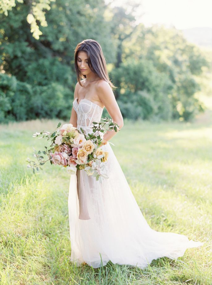 bride in grassy field with bouqet
