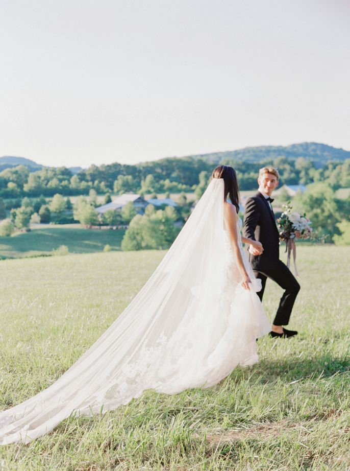 groom leading the bride through field