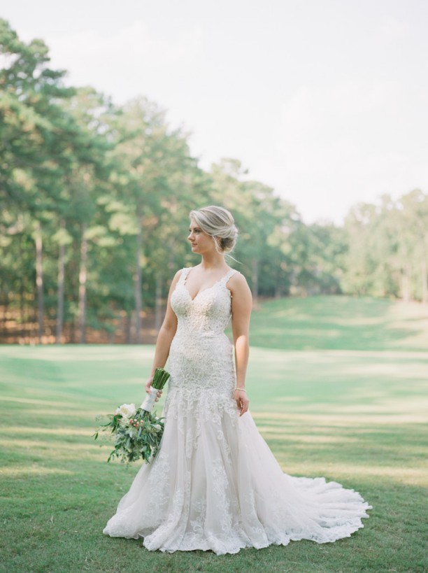 bride holding bouquet standing in grass field