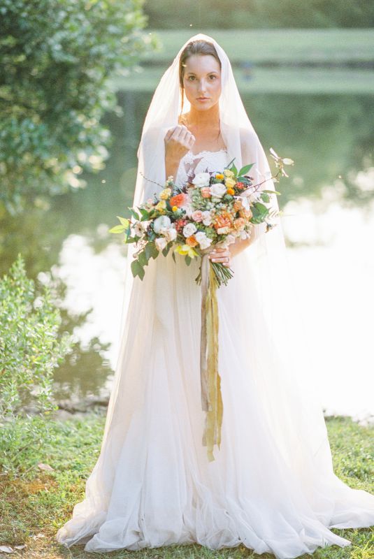 bride holding bouquet in front of a lake