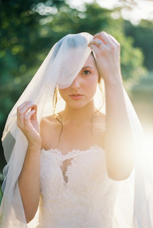 bride lifting veil to reveal beautiful makeup