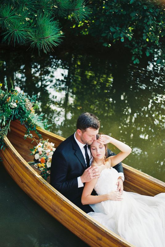 bride leaning on groom in a canoe
