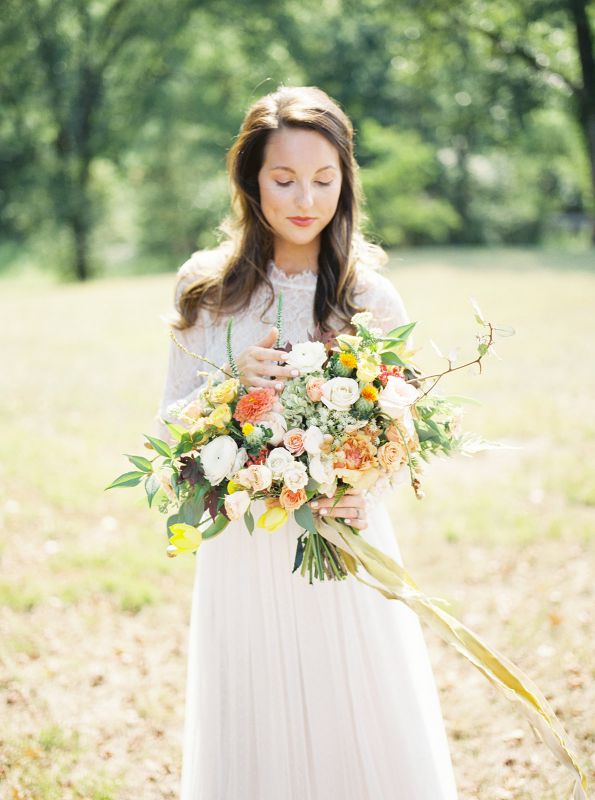bride holding bouquet in grass field with hair down