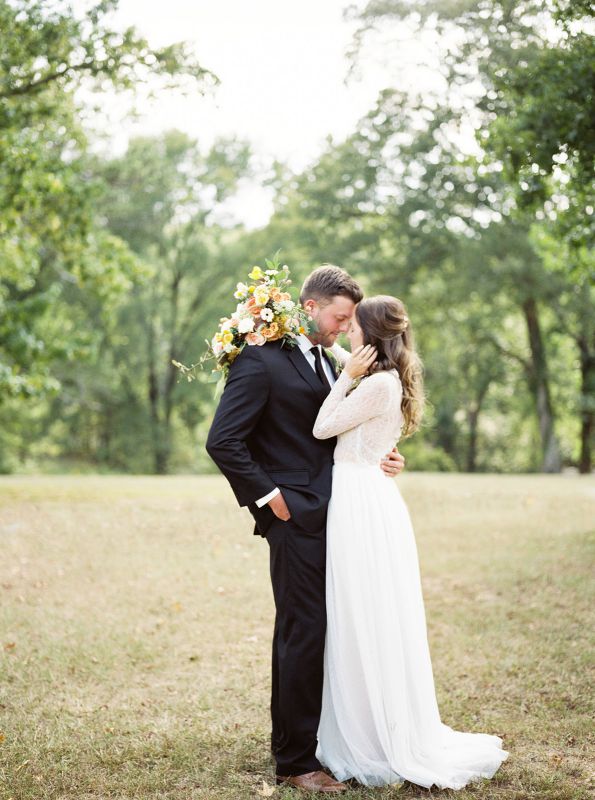 bride and groom embracing in grass field