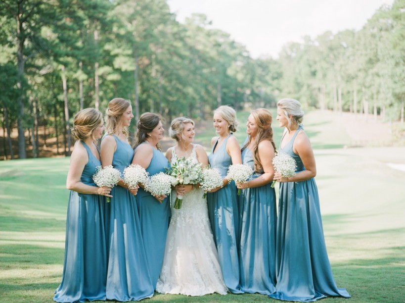 beautiful bride and bridesmaids posing in a grassy field