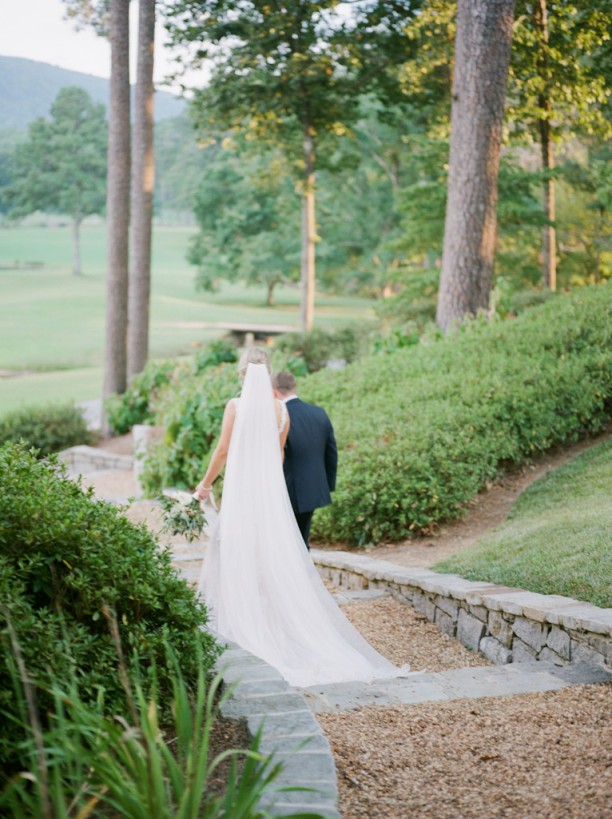 bride and groom holding hands walking down path