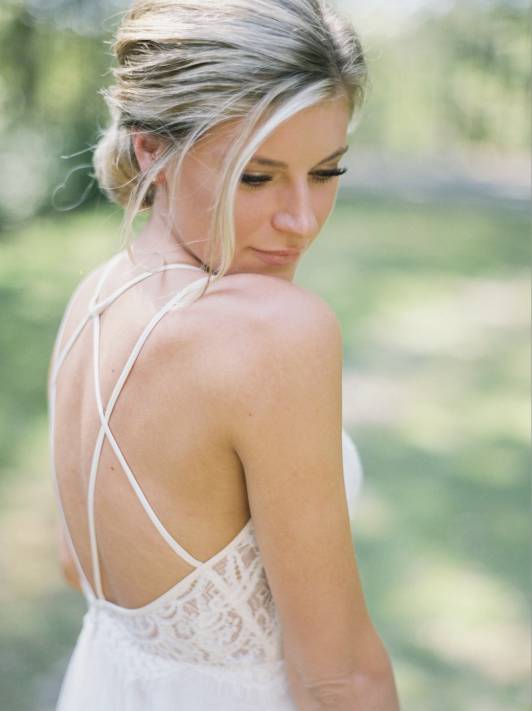A bride in a white wedding dress softly looking at the camera to show off her glowing makeup and styled hair.