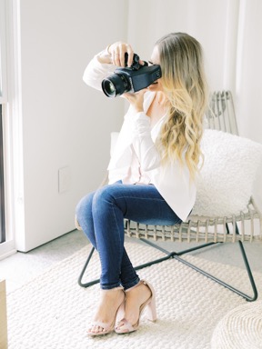 Photographer looking through her camera white sitting on a chair