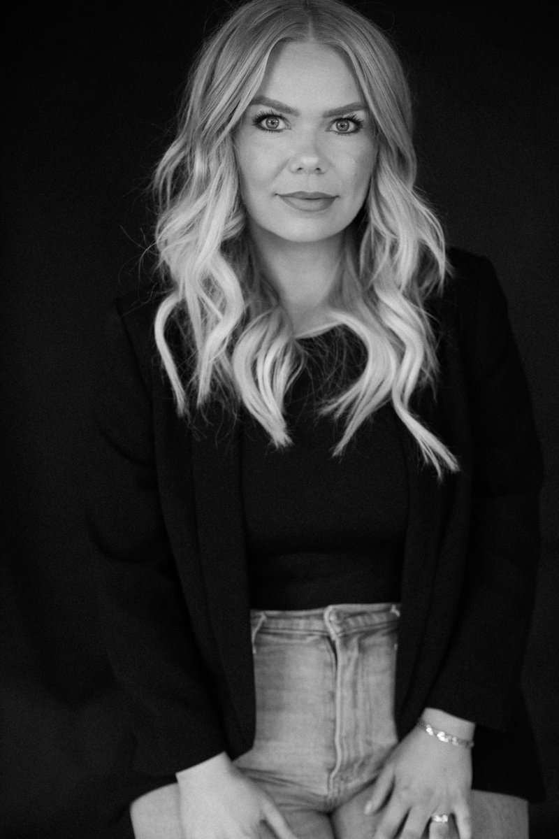 Woman with styled hair smiling on a black backdrop.