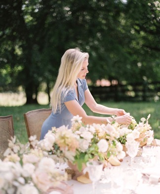 Wedding planner arranging wedding flowers on a table before the rehearsal dinner.